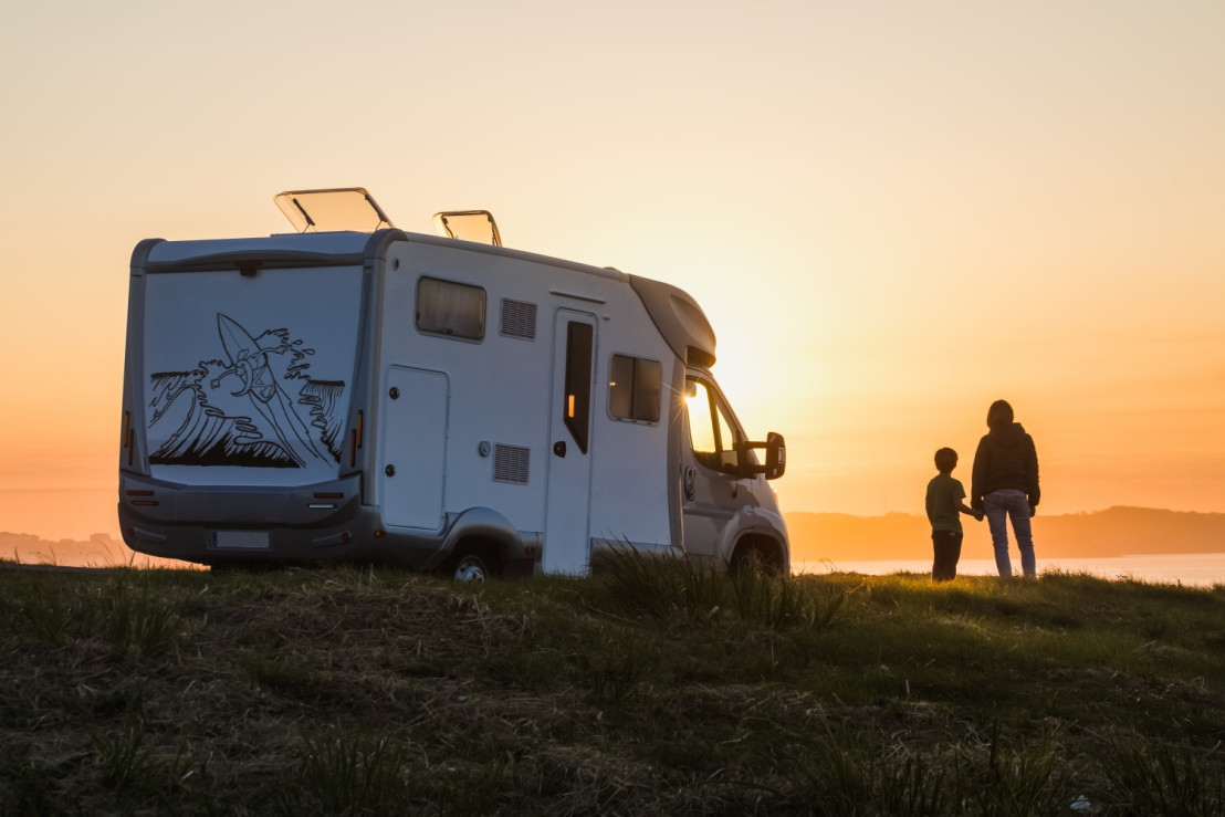 Camper met uitzicht op heuvel met ondergaande zon