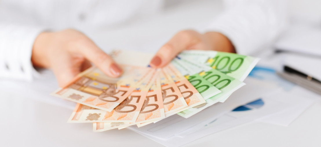 Man laat een stapeltje briefgeld zien in euro's met biljetten van 100 euro en 50 euro