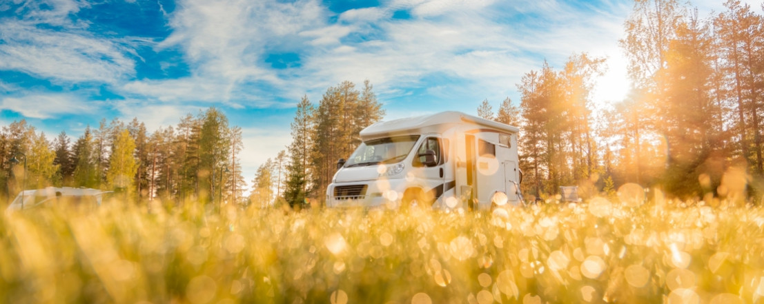 Camper staat op een veld met daarboven een prachtige lucht