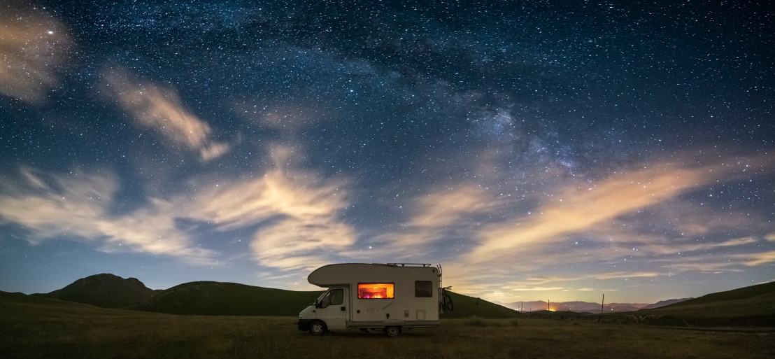 Een alkoof camper staat onder een prachtige heldere sterrenhemel