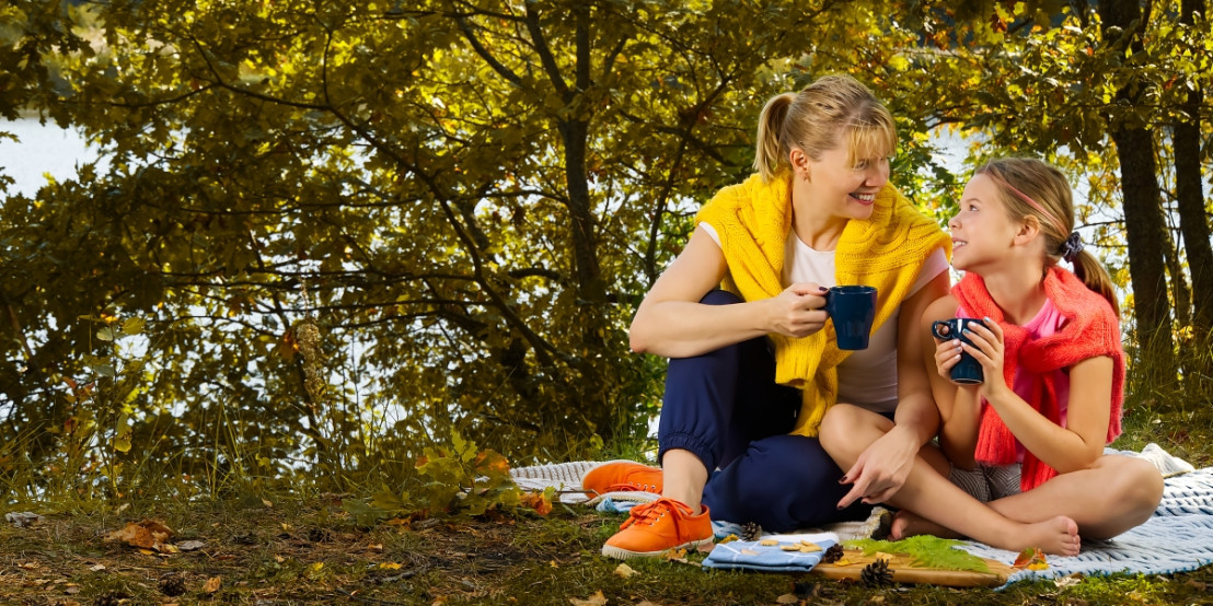 Vrouw drinkt met dochter een kopje koffie op een camping tijdens de camperreis