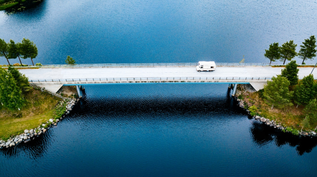 Camper die gehuurd is rijdt over een brug bij een meer in Scandinavië