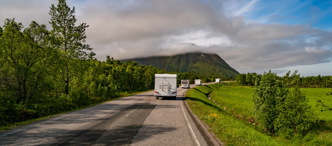 Een drukbezochte camperroute waarbij er meerdere campers achter elkaar aan rijden.