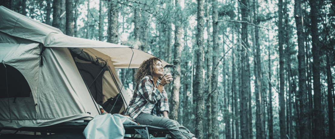 Vrouw met daktent op de auto parkeert op een unieke campspace