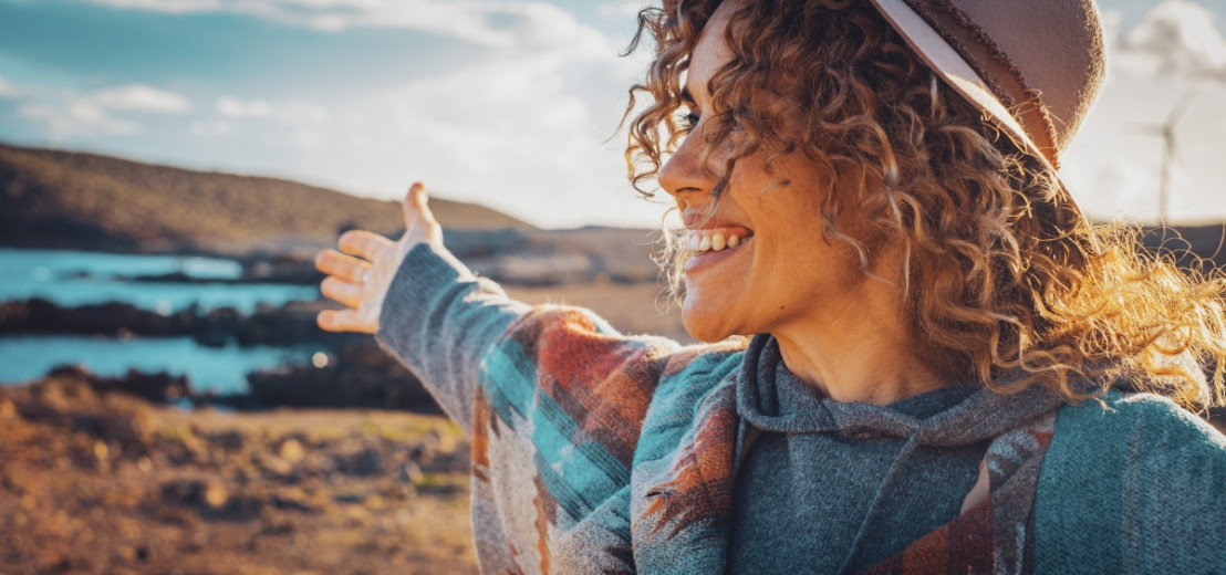 Vrouw geniet met een grote glimlach tijdens een camperreis door prachtige natuur van Frankrijk