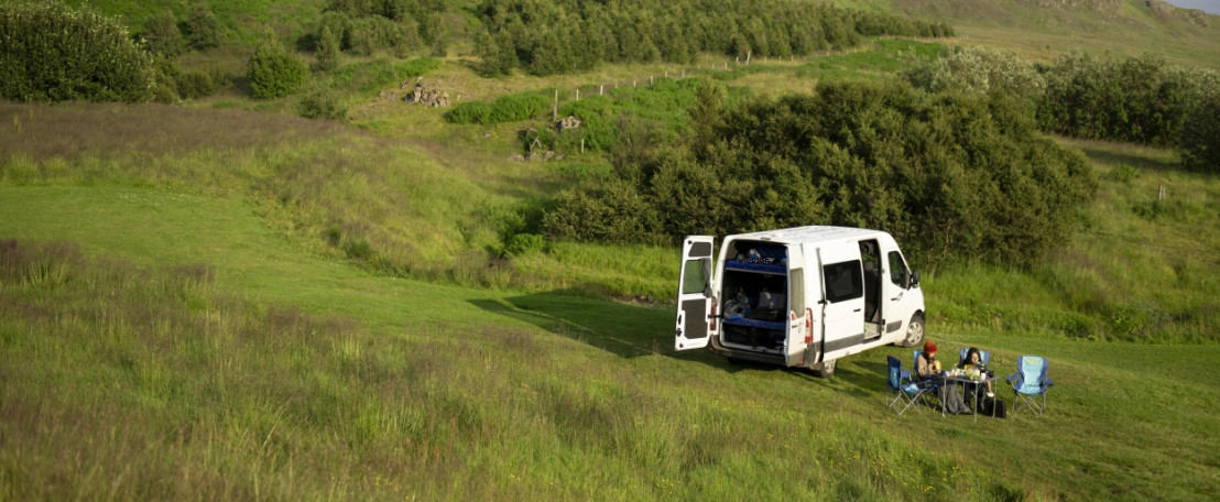 Buscamper staat midden in de natuur met prachtig utizicht op groene heuvels